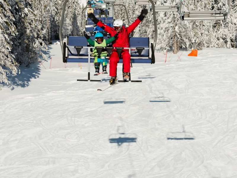 Little boy with ski instructor enjoying on ski lift