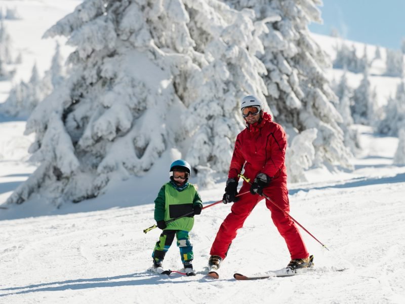 Ski instructor teaching little boy skiing